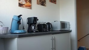 Una encimera de cocina con cafetera, tostadora y microondas.