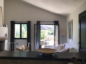 A modern interior with a kitchen counter, dining area, and a view of the outdoor patio. - Charming little house in a natural, peaceful setting with a view of the sea in Les Restanques, near Grasse (Grasse)