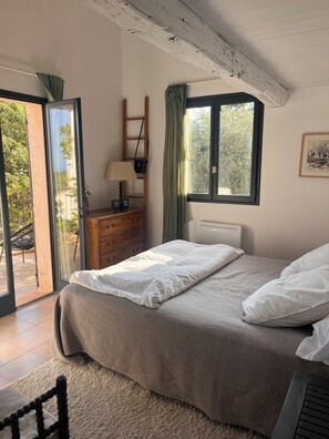 Une chambre à coucher avec un lit, une commode, une lampe, une fenêtre et une vue sur l’extérieur.