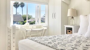 Un dormitorio con cama, escritorio y ventana.