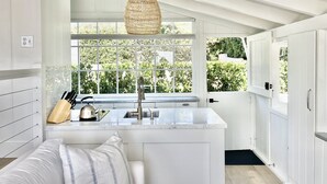 Una cocina moderna con un ventanal grande, armarios blancos y una lámpara colgante.