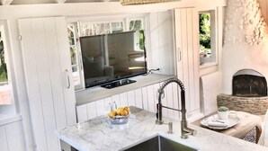 Una cocina moderna con armarios blancos, encimera de mármol, horno empotrado, un lavabo y una lámpara colgante.