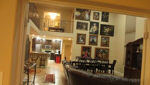 Un vaste espace de vie doté d’un plafond haut, une table à manger dressée pour quatre personnes et une cuisine en arrière-plan.