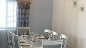 A dining room with a round table, six chairs, and a chandelier.