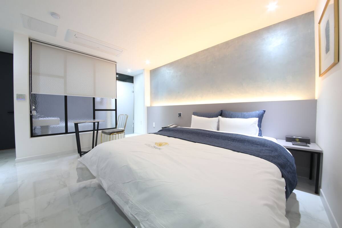 Un dormitorio moderno con una cama grande, una mesita de noche, una silla y un armario empotrado.
