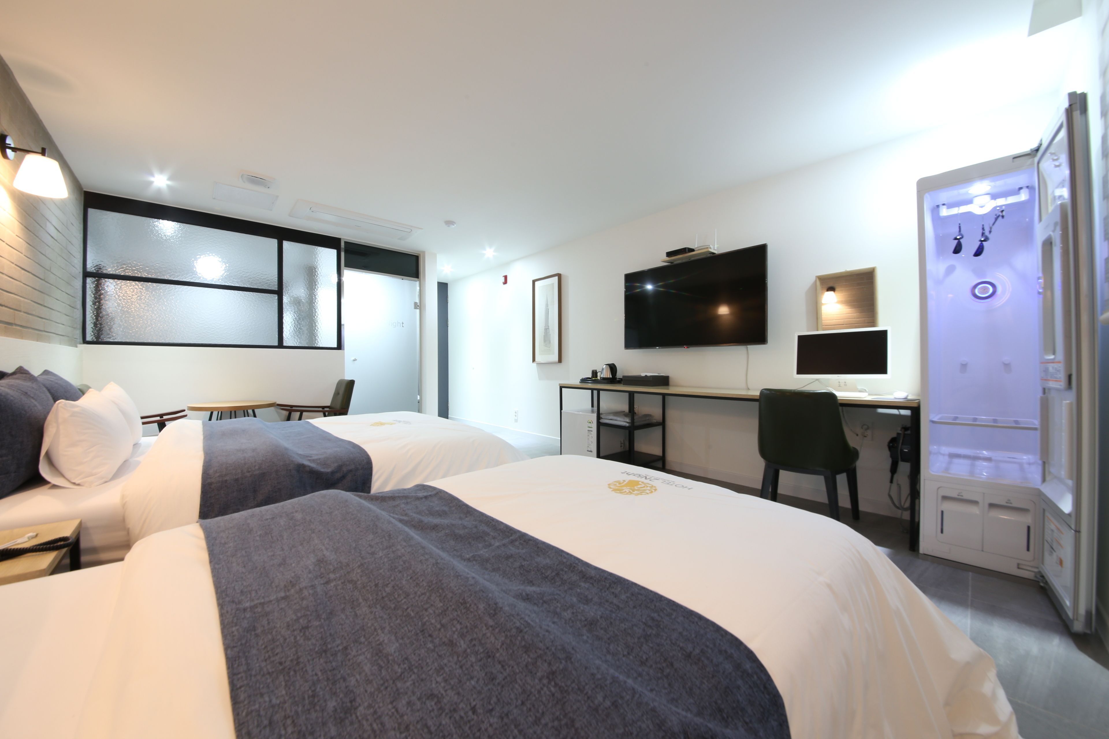 Habitación de hotel con dos camas, un escritorio, una silla, un televisor y un minibar.