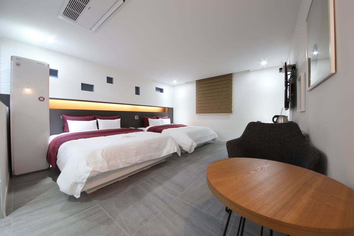 Una habitación de hotel moderna con dos camas, una mesa de madera y una zona de estar.