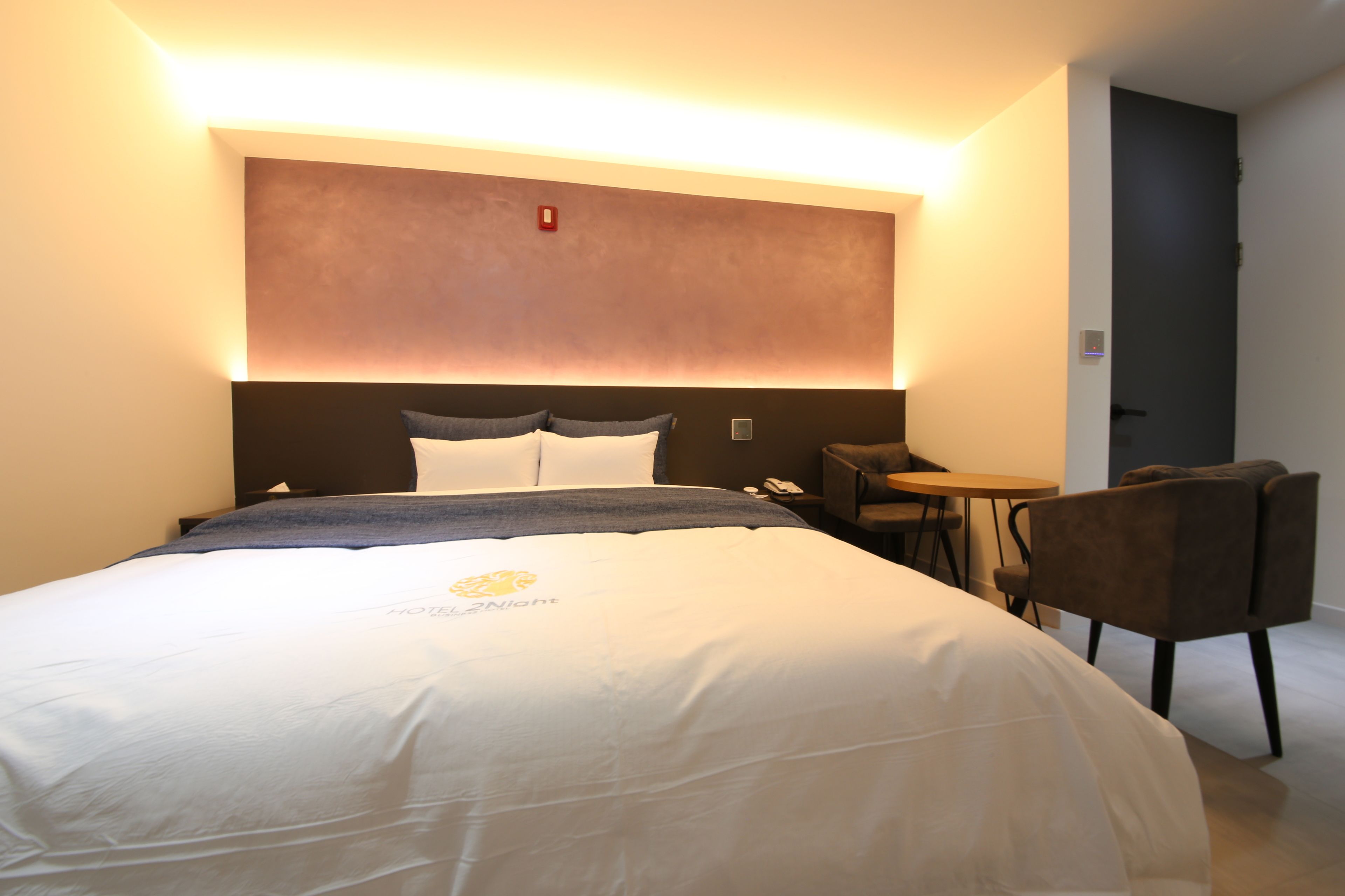 Une chambre d’hôtel avec un grand lit, une table de chevet, une chaise et une petite table.