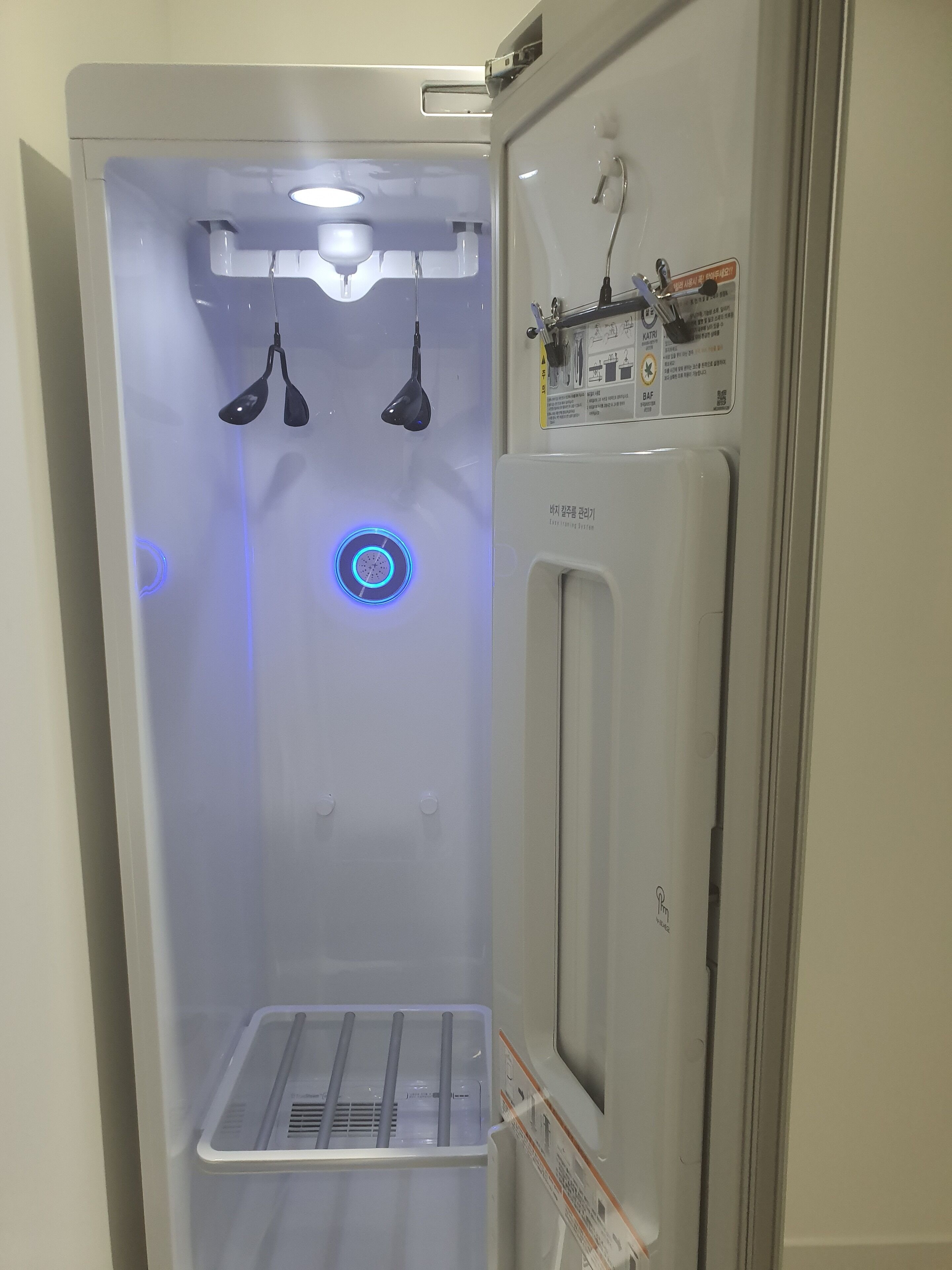 A compact, well-lit room with a built-in air conditioning unit, a small window, and a door with a handle.