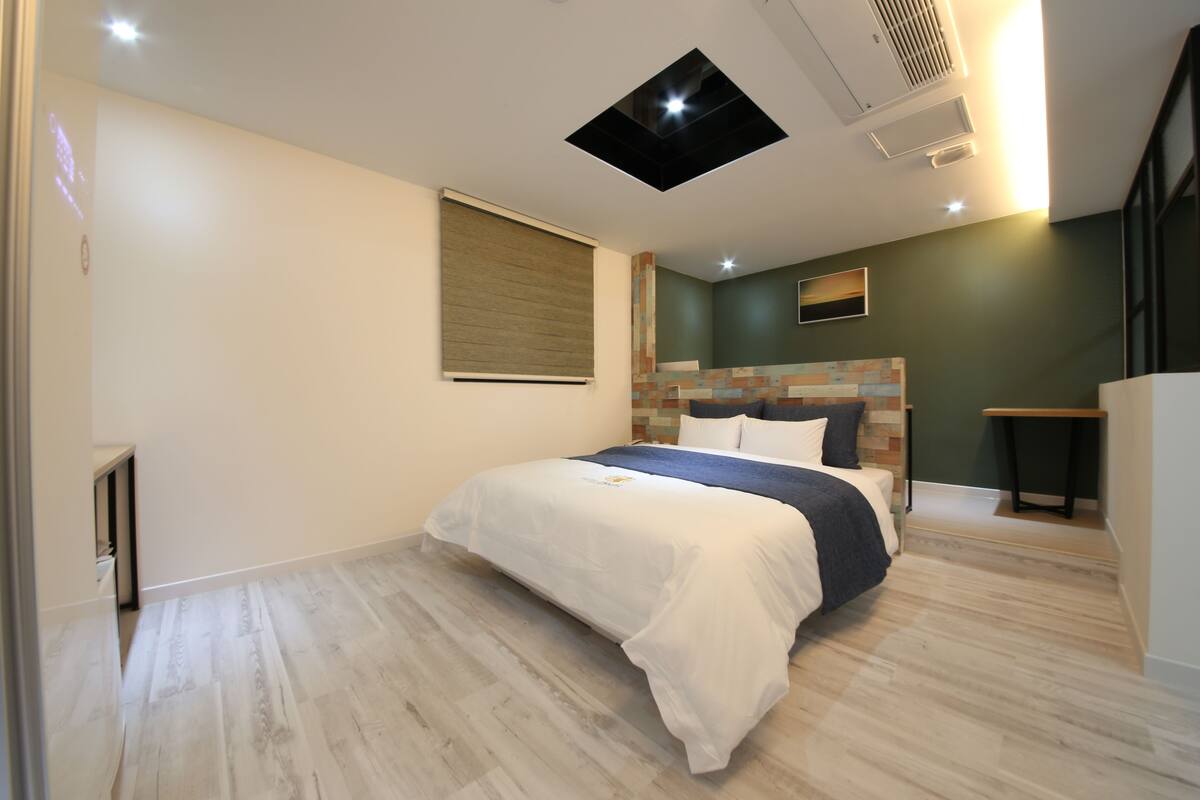 Un dormitorio moderno con cama, cabecera de mosaico, mesita de noche y estante empotrado.