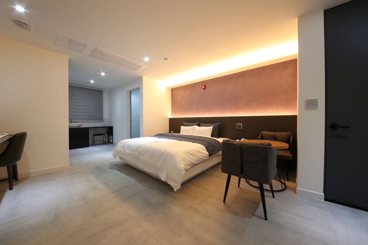 Un dormitorio moderno con una cama grande, un escritorio y una zona de comedor.