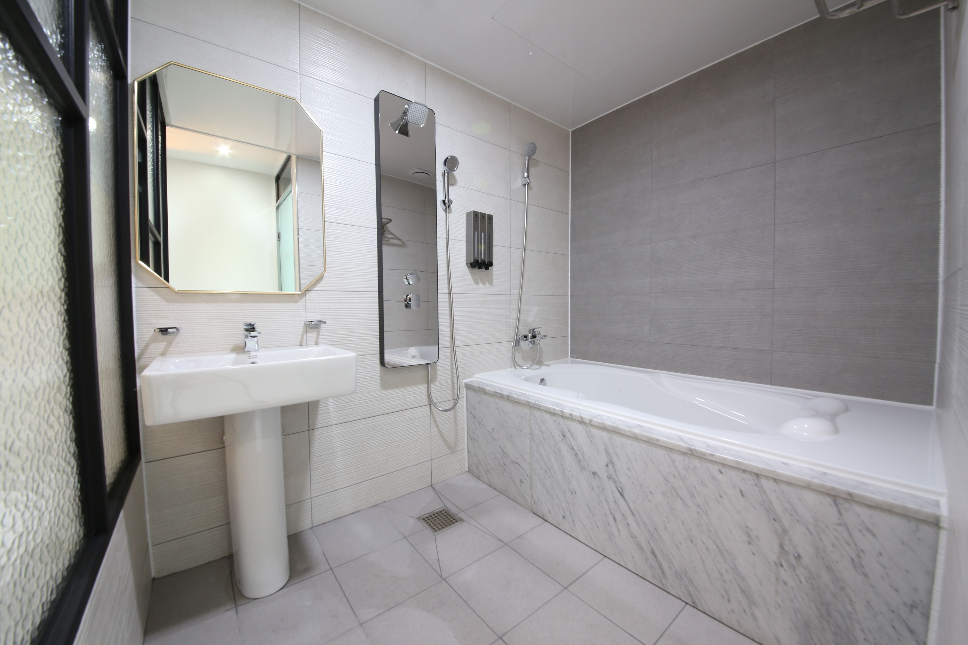 A modern bathroom with a white sink, a large mirror, a shower, and a bathtub.