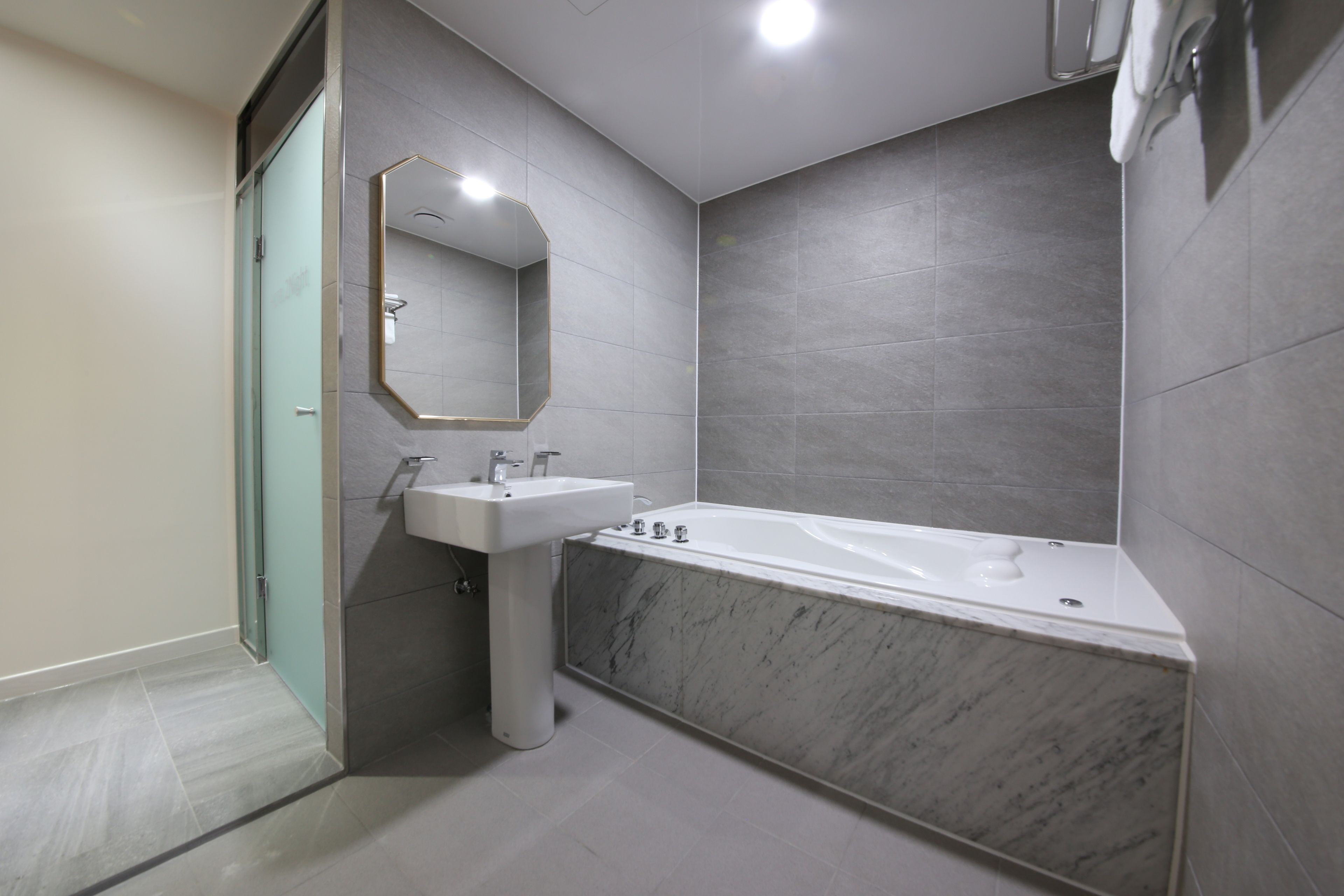 Un baño moderno con una bañera de mármol, un lavabo y una ducha con mampara de vidrio.