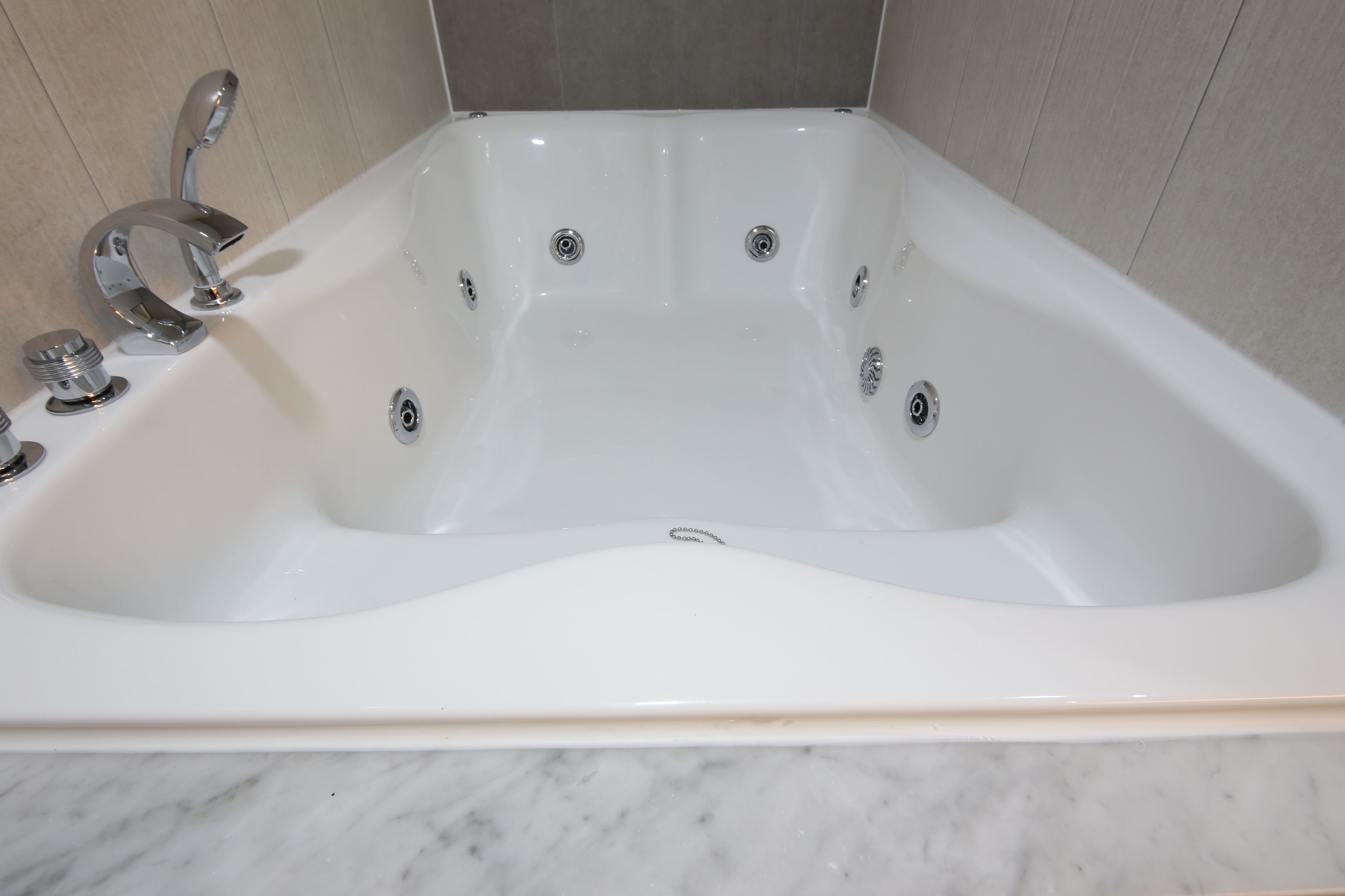 Una bañera blanca con dos grifos y un desagüe.