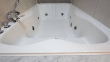Una bañera blanca con dos grifos y un desagüe.