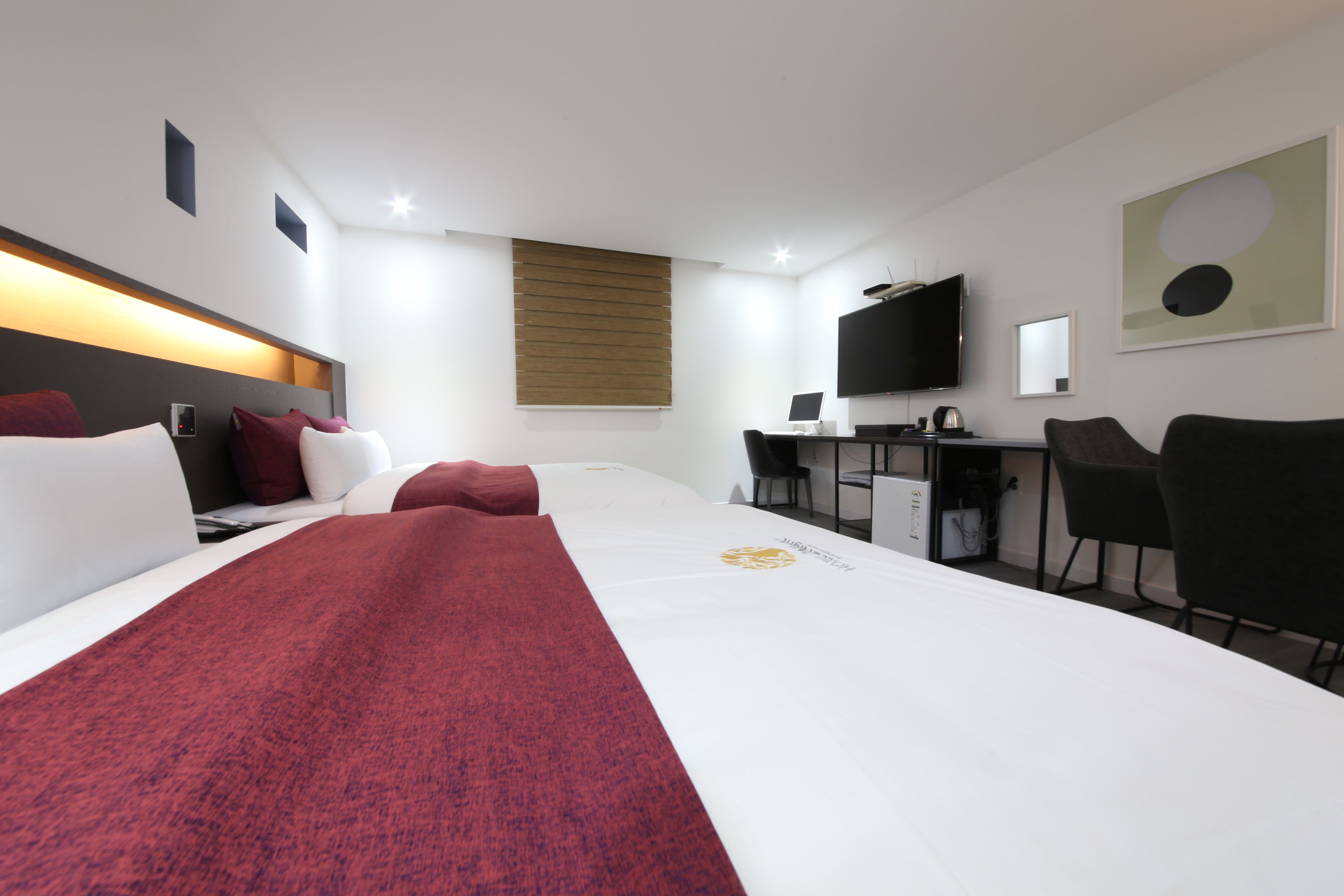A hotel room with a large bed, a desk with a computer, a TV, and a chair.