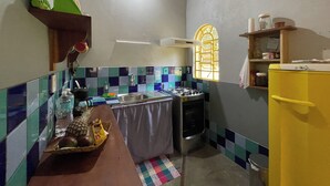 A compact kitchen with a gas stove, a sink, and a window with a metal grille.