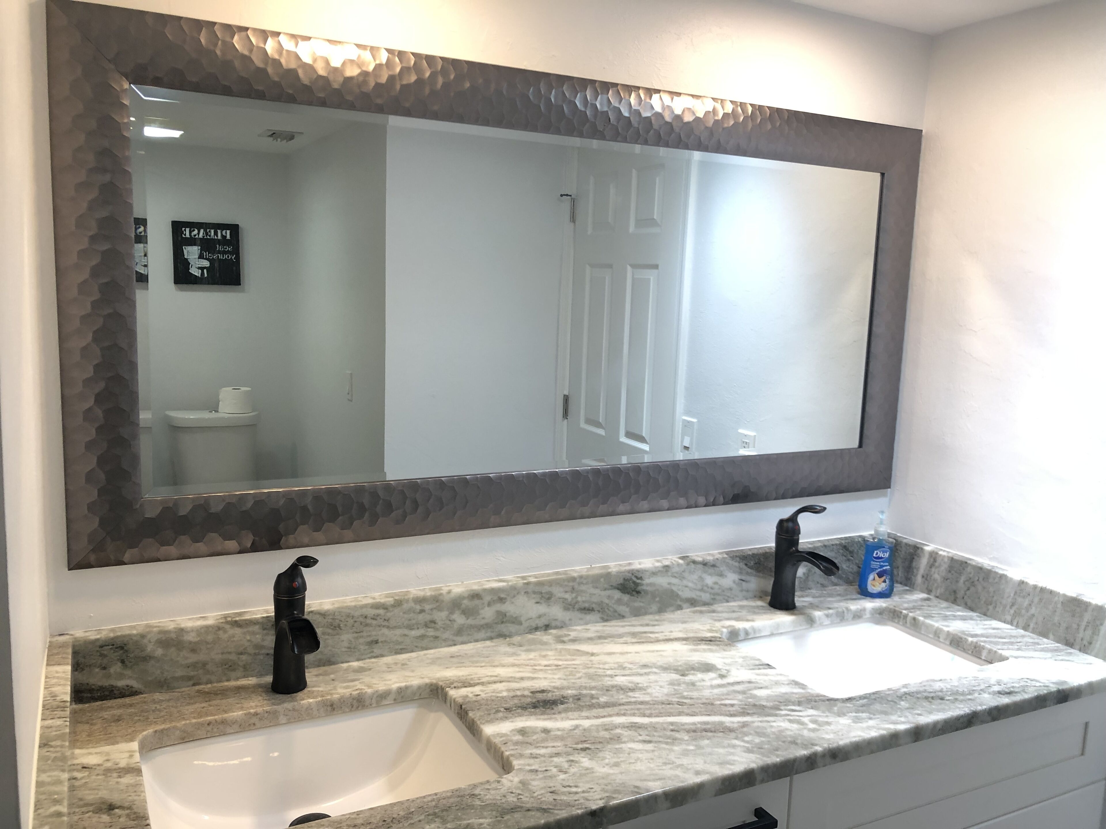 A bathroom with a large mirror, two sinks, and a toilet.