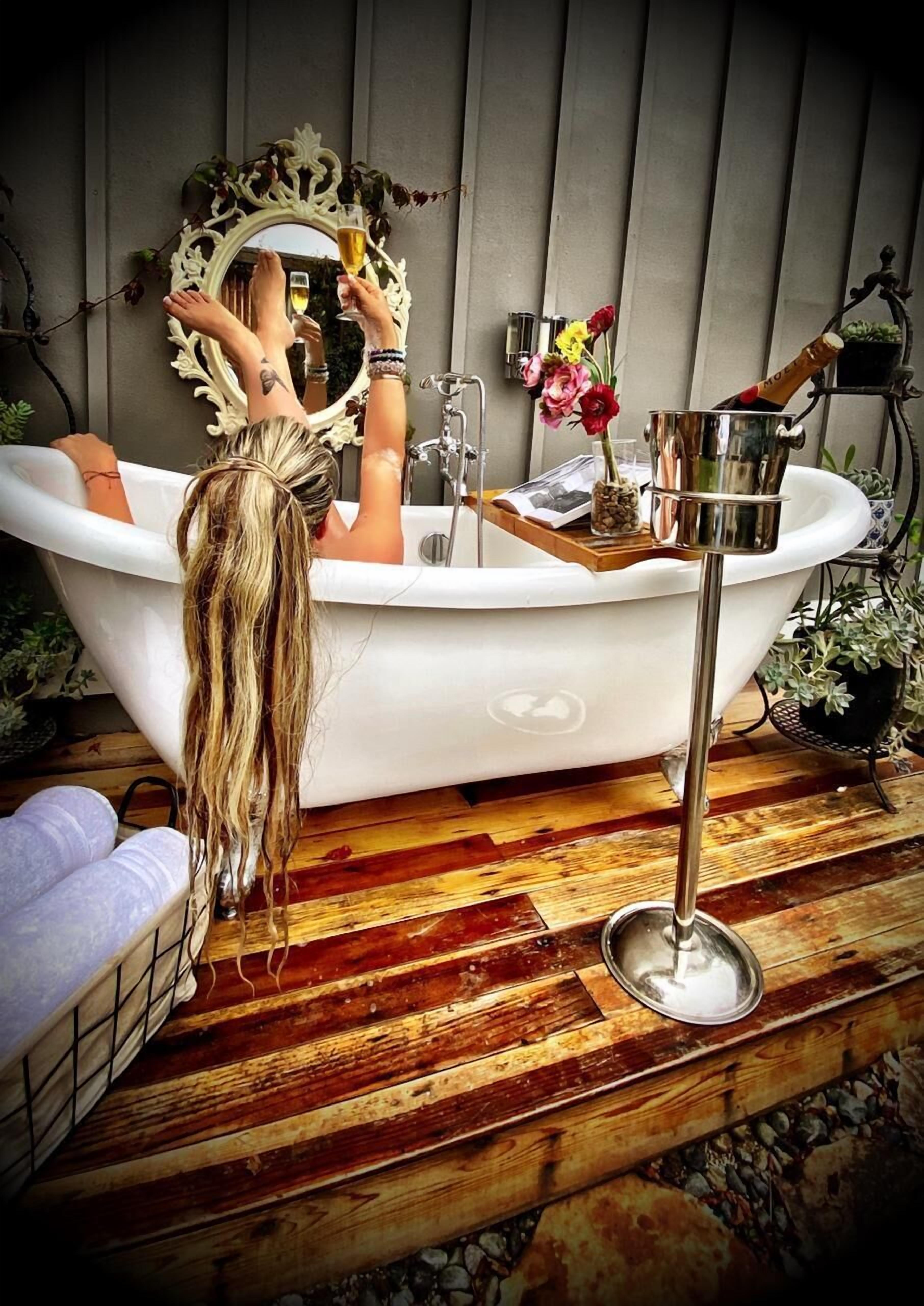 Eine Badewanne mit Spiegel, einer Champagnerflasche und Blumen.
