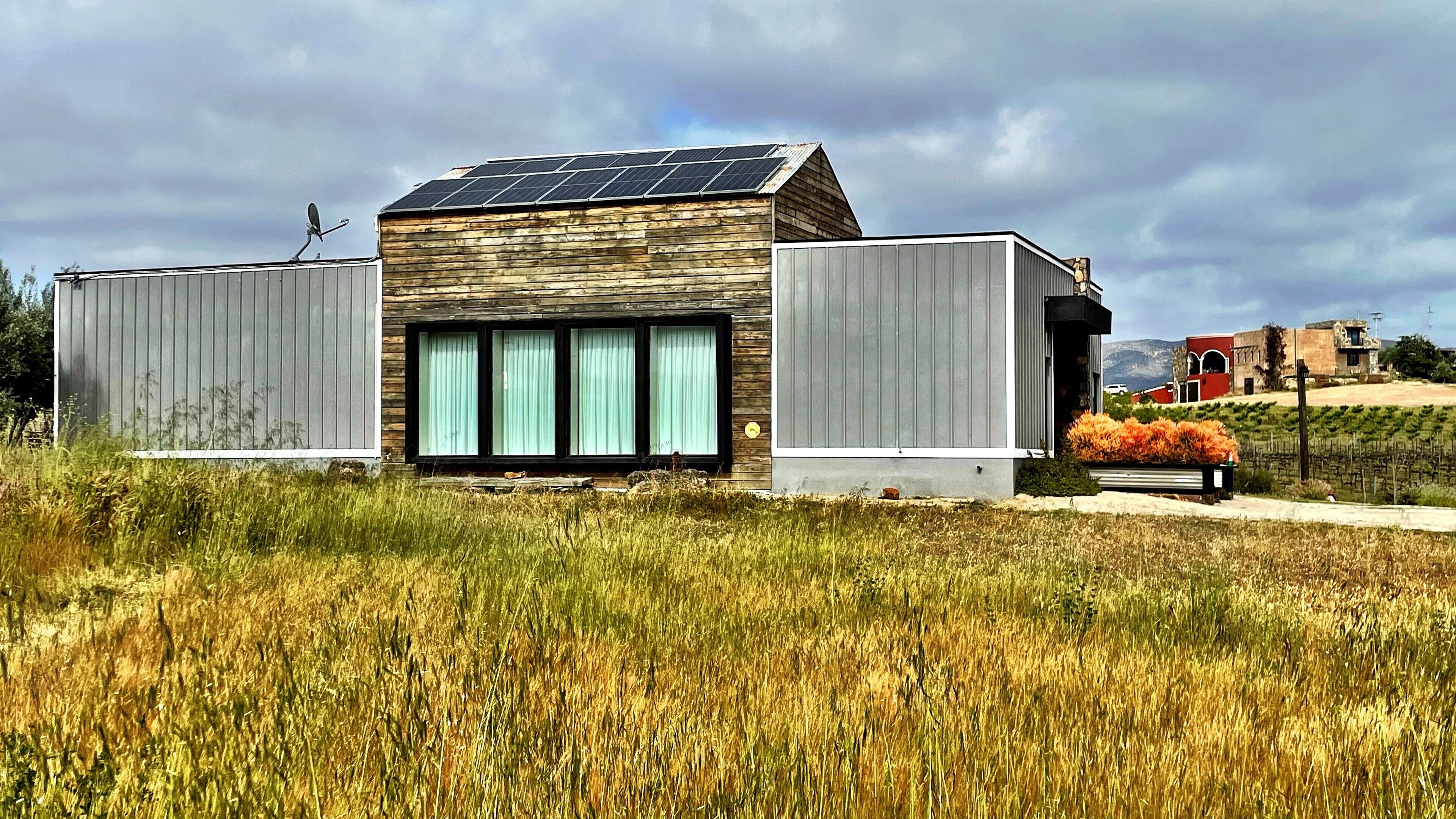 Un edificio moderno con techo inclinado, ventanas amplias y paneles solares.