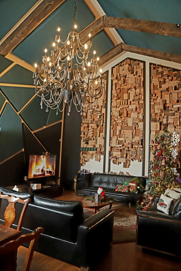 Un salon chaleureux avec un grand lustre, une cheminée et un sapin de Noël décoré.