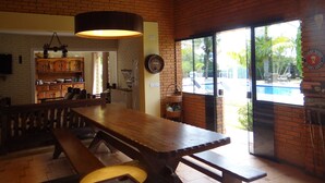 Een restaurant met bakstenen muren, een houten tafel en uitzicht op een zwembad.