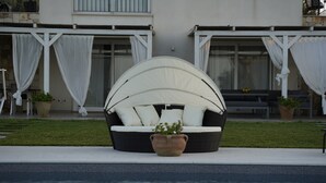 Un área de estar junto a la piscina con un banco acolchado y una sombrilla grande.