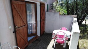 A small outdoor patio with a table and chairs, a wooden door, and a concrete wall.