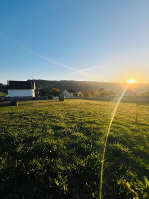 A grassy field with a building in the distance and a clear sky.