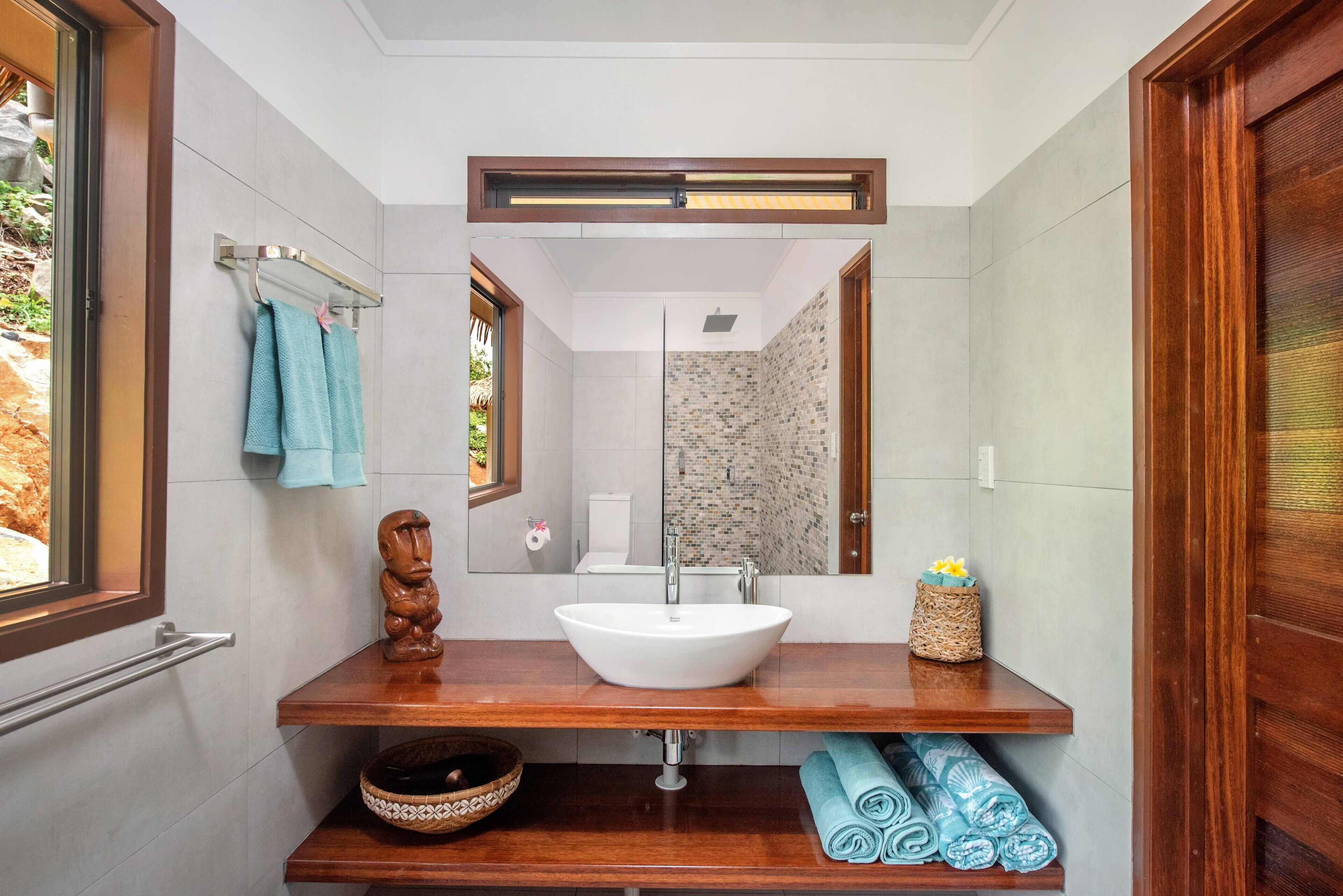 Une salle de bain avec un meuble-lavabo en bois, un lavabo blanc, un miroir et un porte-serviettes.