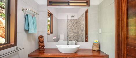 Une salle de bain avec un meuble-lavabo en bois, un lavabo blanc, un miroir et un porte-serviettes.