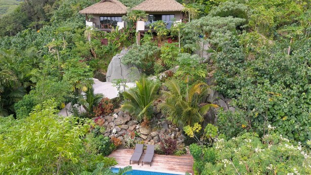 A lush, tropical resort with two thatched-roof villas, a swimming pool, and dense greenery. - Rainbow Villas (Rarotonga)