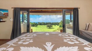 A bedroom with a large bed, a view of a golf course, and a balcony with curtains. - Rainbow Villas (Rarotonga)