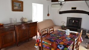 A cozy room with a wooden dining table, a sofa, a fireplace, and a kitchen area. - Gîte in the heart of the Lozère Cévennes (La Falguière)