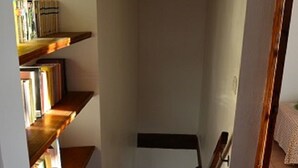 A staircase with wooden steps and a handrail, leading to a landing with a white wall and a hanging light fixture. - Gîte in the heart of the Lozère Cévennes (La Falguière)