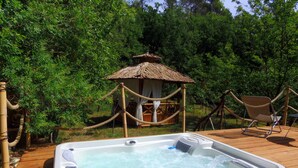 Un jacuzzi en una terraza de madera rodeado de vegetación exuberante.