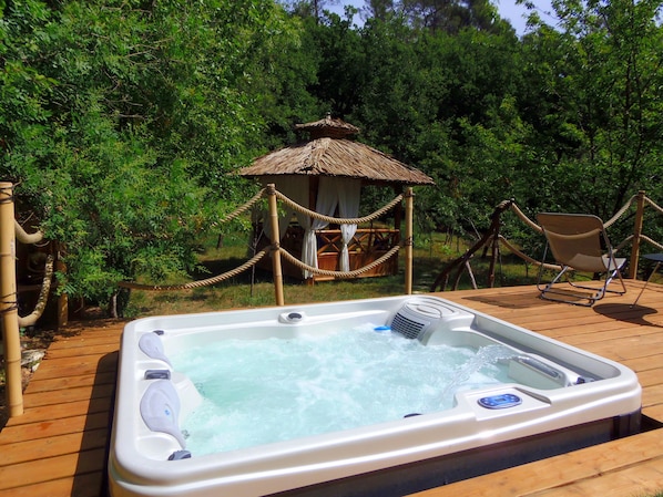 A hot tub on a wooden deck surrounded by lush greenery.