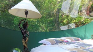 Una cama con un edredón, una lámpara y una pequeña estatua en una mesita de noche.