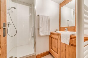 Un baño con cabina de ducha de vidrio, tocador de madera y un espejo grande.