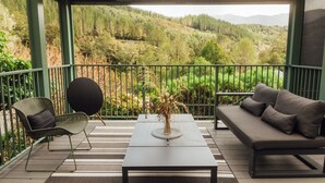 A balcony with a sofa, a chair, and a table with a vase. - Maruia River Retreat (Shenandoah)