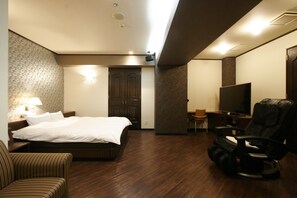A hotel room with a bed, a TV, a massage chair, and a desk. - Hotel NOA - Adults Only (Anjo)