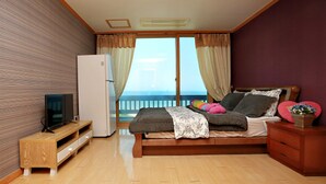 A bedroom with a bed, a television, a refrigerator, and a window with curtains. - Marronnier Pension (Taean)