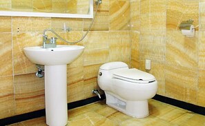 Une salle de bain avec un lavabo blanc, des toilettes et un miroir au mur.
