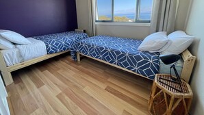 A small room with two single beds, a window with a view, and a wooden floor. - Freycinet Dream (Coles Bay)