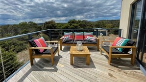 A wooden deck with outdoor seating and a glass balustrade. - Freycinet Dream (Coles Bay)