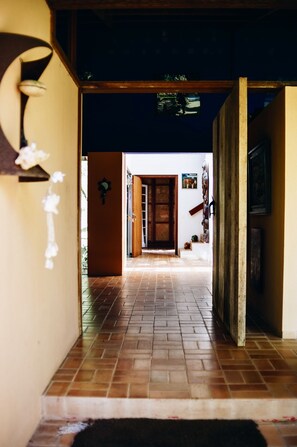 A hallway with a tiled floor leading to a wooden door. - Beautiful house in Ilhabela (Ilhabela)
