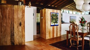 A wooden interior with a dining area, a wooden door, and a framed picture on the wall. - Beautiful house in Ilhabela (Ilhabela)