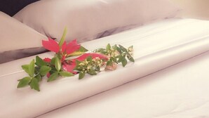 A neatly made bed with white linens and a decorative floral arrangement on the bed. - Green Lodge Holiday Homes (Nuku'alofa)