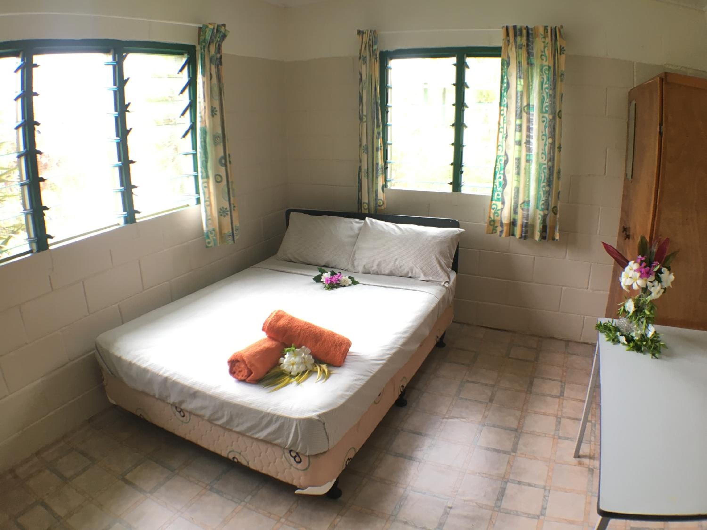 A single-bed room with a bed, a small table, and a window with curtains.