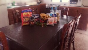 A dining table with food items and a microwave in a kitchen. - Green Lodge Holiday Homes (Nuku'alofa)